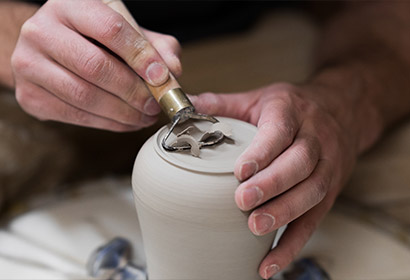 Hands scultping a clay vessel