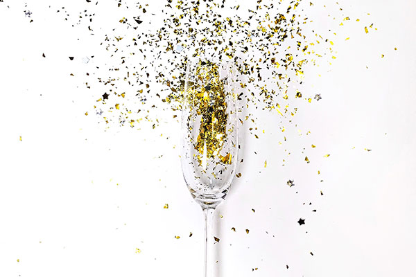 A champagne glass with confetti exploding out of it