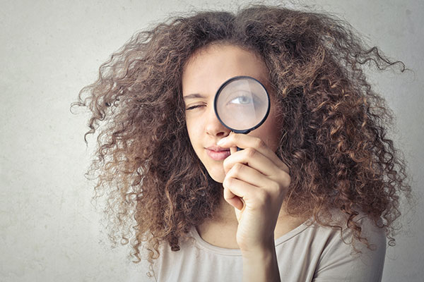 A young woman looking through a magnifying glass